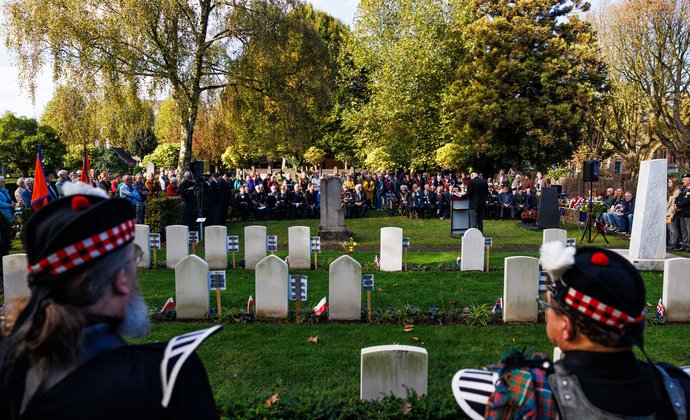 Bezoekers luisteren naar een toespraak bij de oorlogsgraven