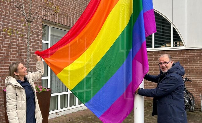 De wethouder toont de gehesen vlag bij het gemeentehuis