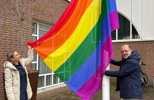 De wethouder toont de gehesen vlag bij het gemeentehuis