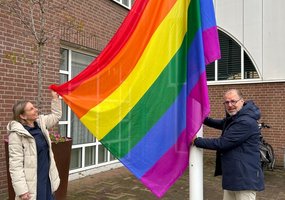 De wethouder toont de gehesen vlag bij het gemeentehuis